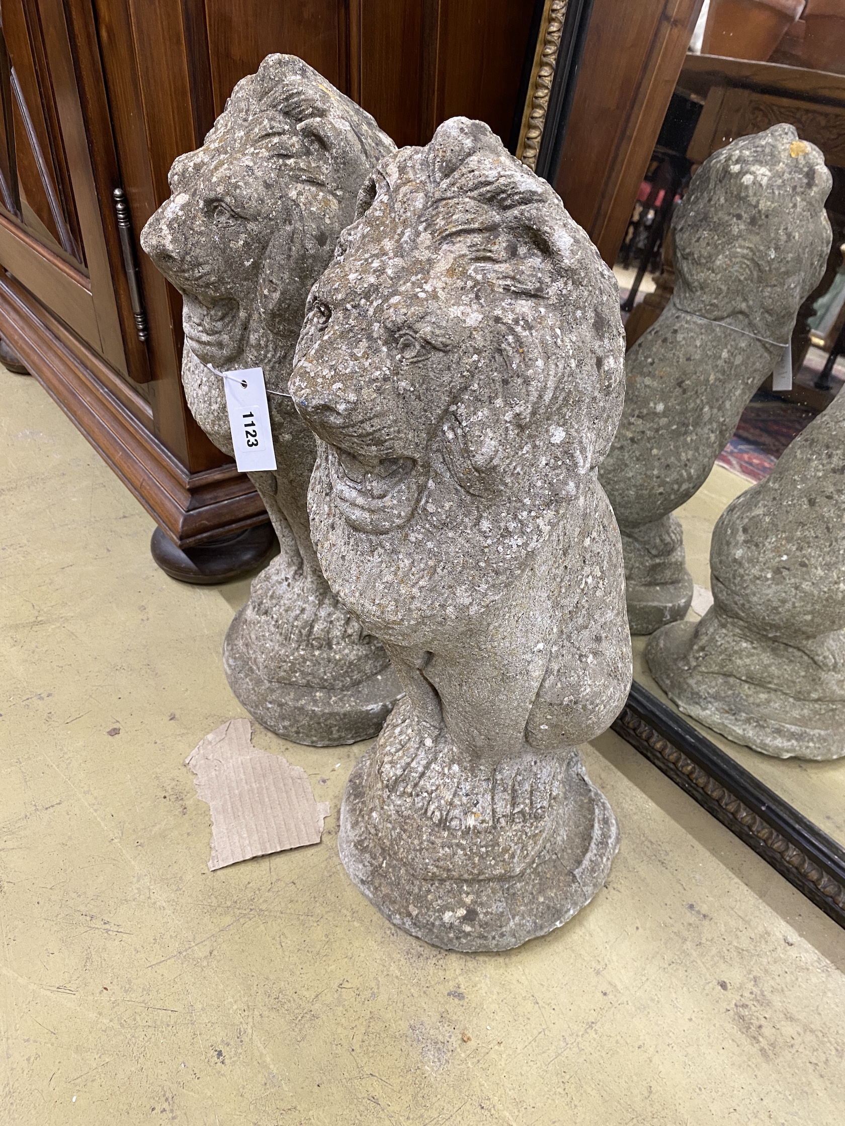 A pair of reconstituted stone seated lion garden ornaments, height 50cm